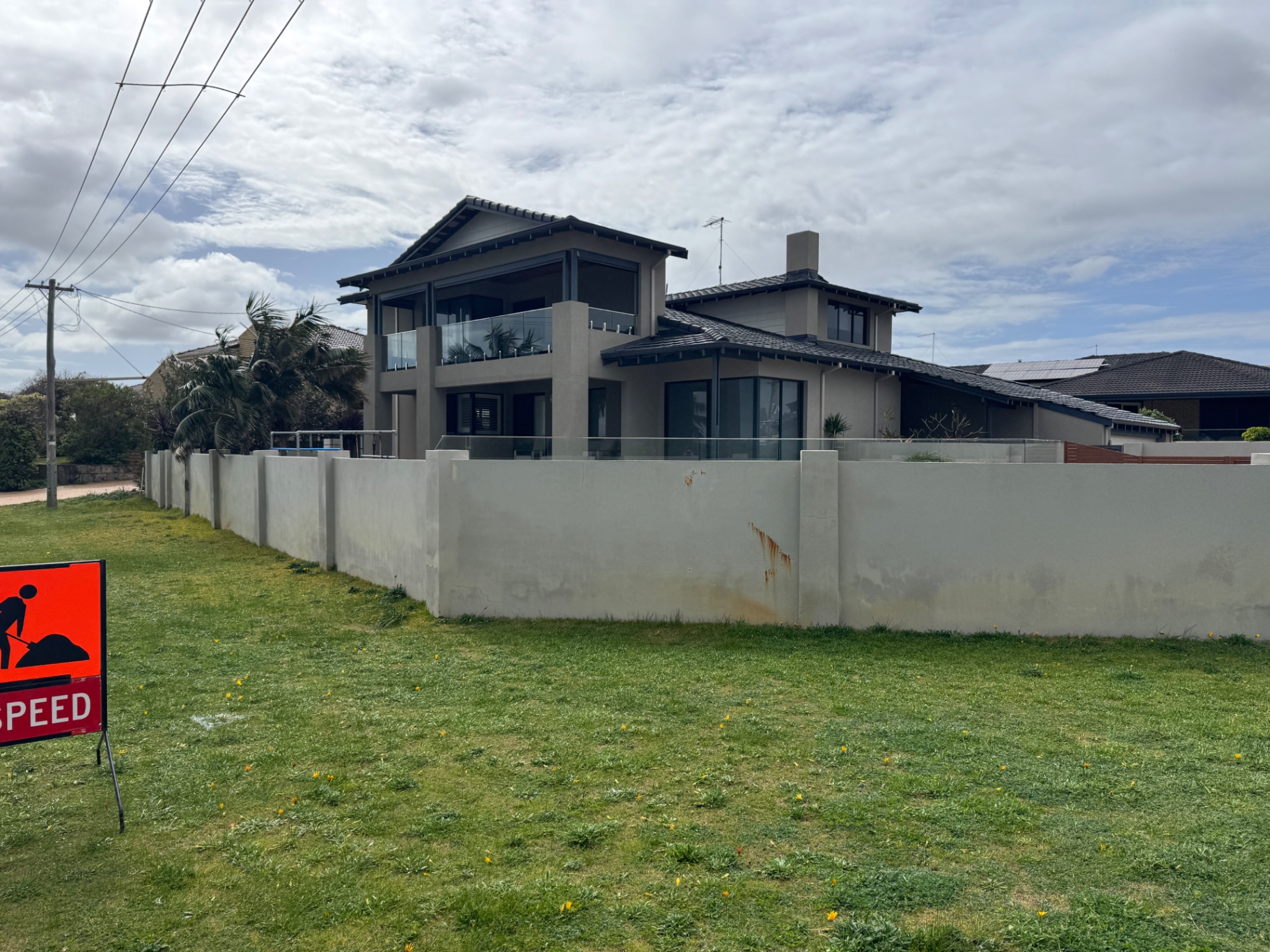 Coastal home before works, showing weathered grey render and stained boundary wall